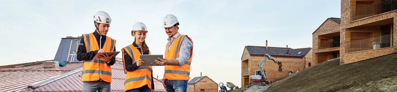 Drei Bauleiter mit Warnweste und Helm auf Baustelle