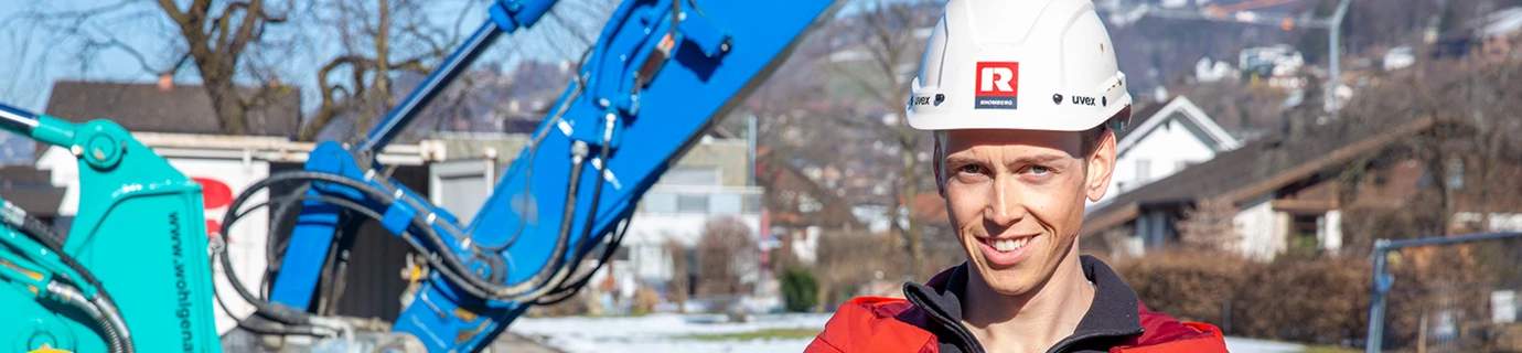 Florian Egle steht vor Bagger auf Baustelle für Web