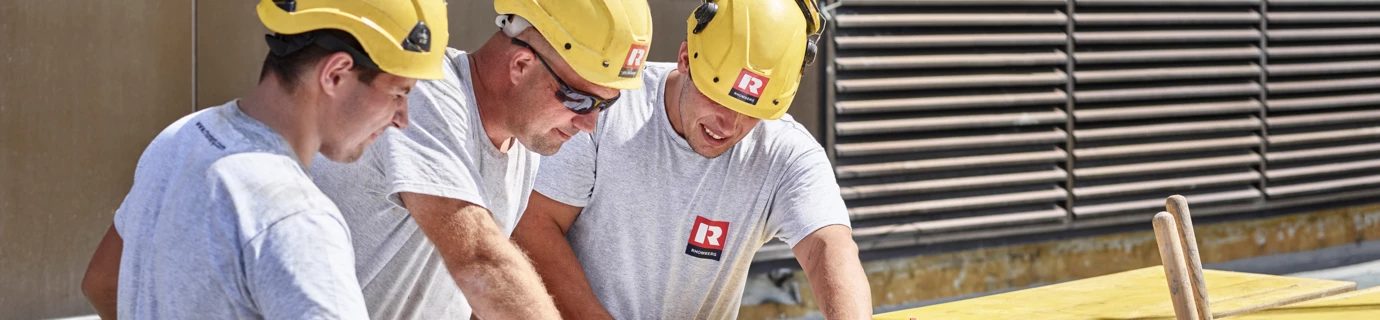 Bauarbeiter stehen vor Plan und diskutieren ihn