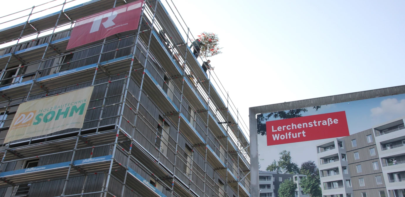 Die erste von zwei Dachgleichen: Der Firstbaum wird auf das fünfstöckige Holzgebäude aufgezogen.