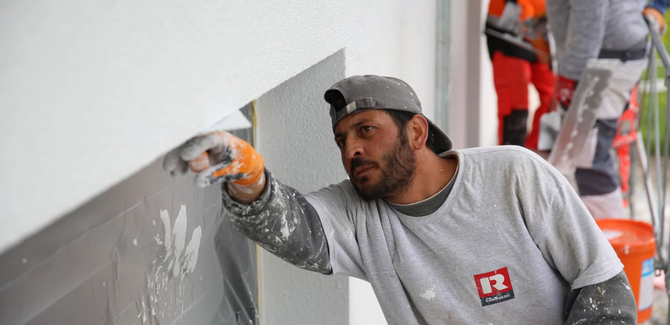 Hochbau Verputzarbeiten Mann verputzt Fenster
