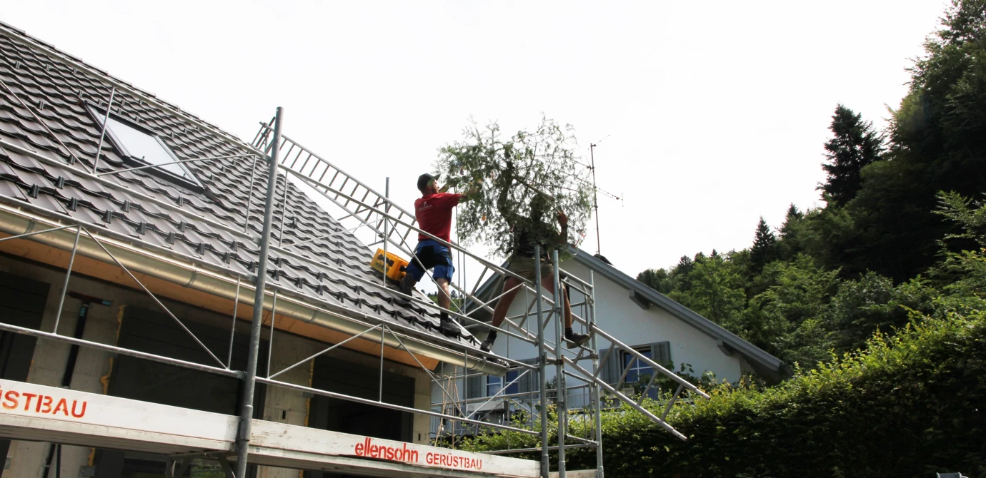Handwerker beim Aufziehen des Firstbaumes auf den Rohbau der Wohnanlage im Dornbirner Eulental.
