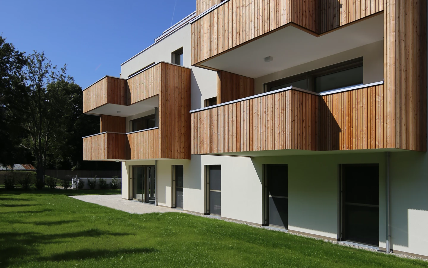 TROY_ALTM (2) Aussenansicht mit Balkons, Wiese und blauem Himmel TROY_ALTM (2) Aussenansicht mit Balkons, Wiese und blauem Himmel
