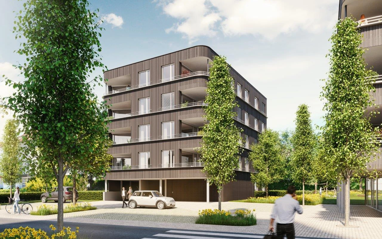 Modernes Wohngebäude Rheindorf mit dunkelbrauner Fassade, Balkonen und Bäumen im Vordergrund, bei Tag unter blauem Himmel.