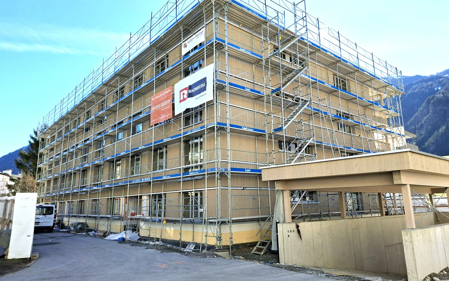Mehrfamilienhaus in Domat/Ems während der Bauphase mit Holzfassade und Gerüst