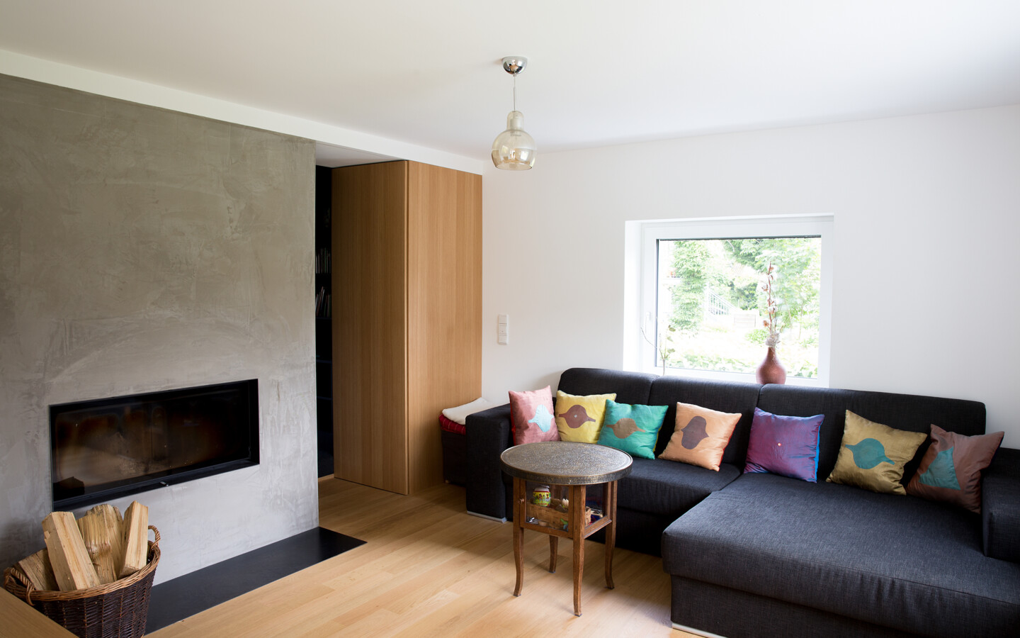 Umbau Einfamilienhaus Greussing-Pallavicini Wohnzimmer mit Couch, Kamin und Hocker