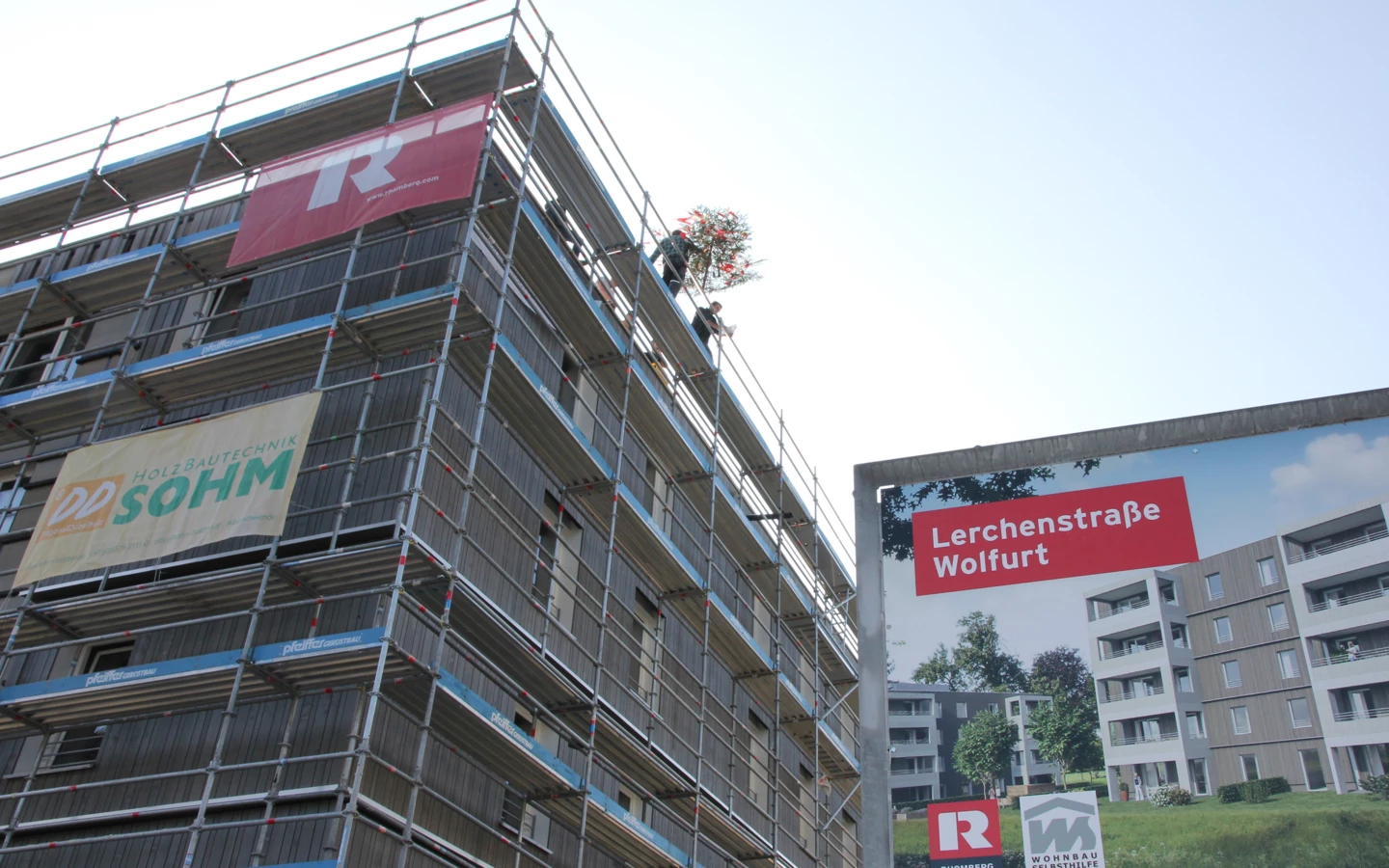 Die erste von zwei Dachgleichen: Der Firstbaum wird auf das fünfstöckige Holzgebäude aufgezogen.