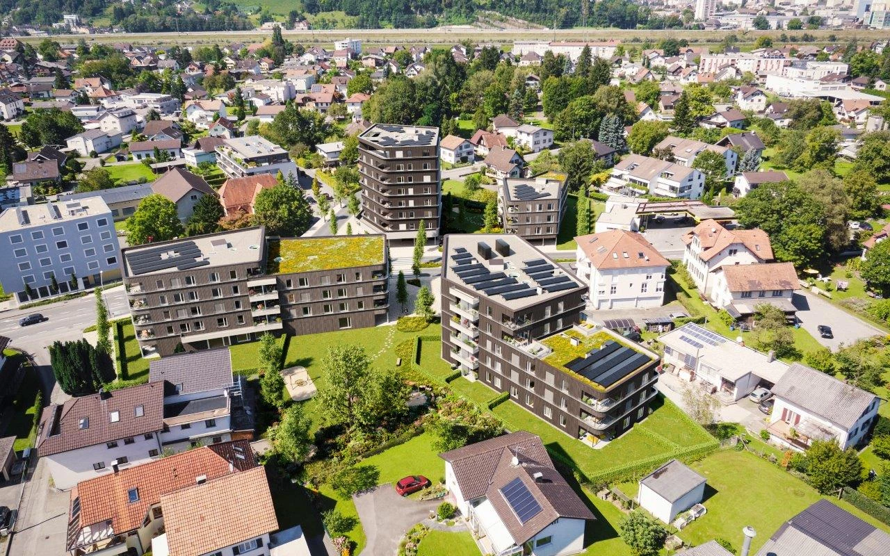 Luftbild des Wohnquartiers Visu Rheindorf mit modernen Gebäuden, Solaranlagen und begrünten Dächern, umgeben von Wohnhäusern und grünen Flächen