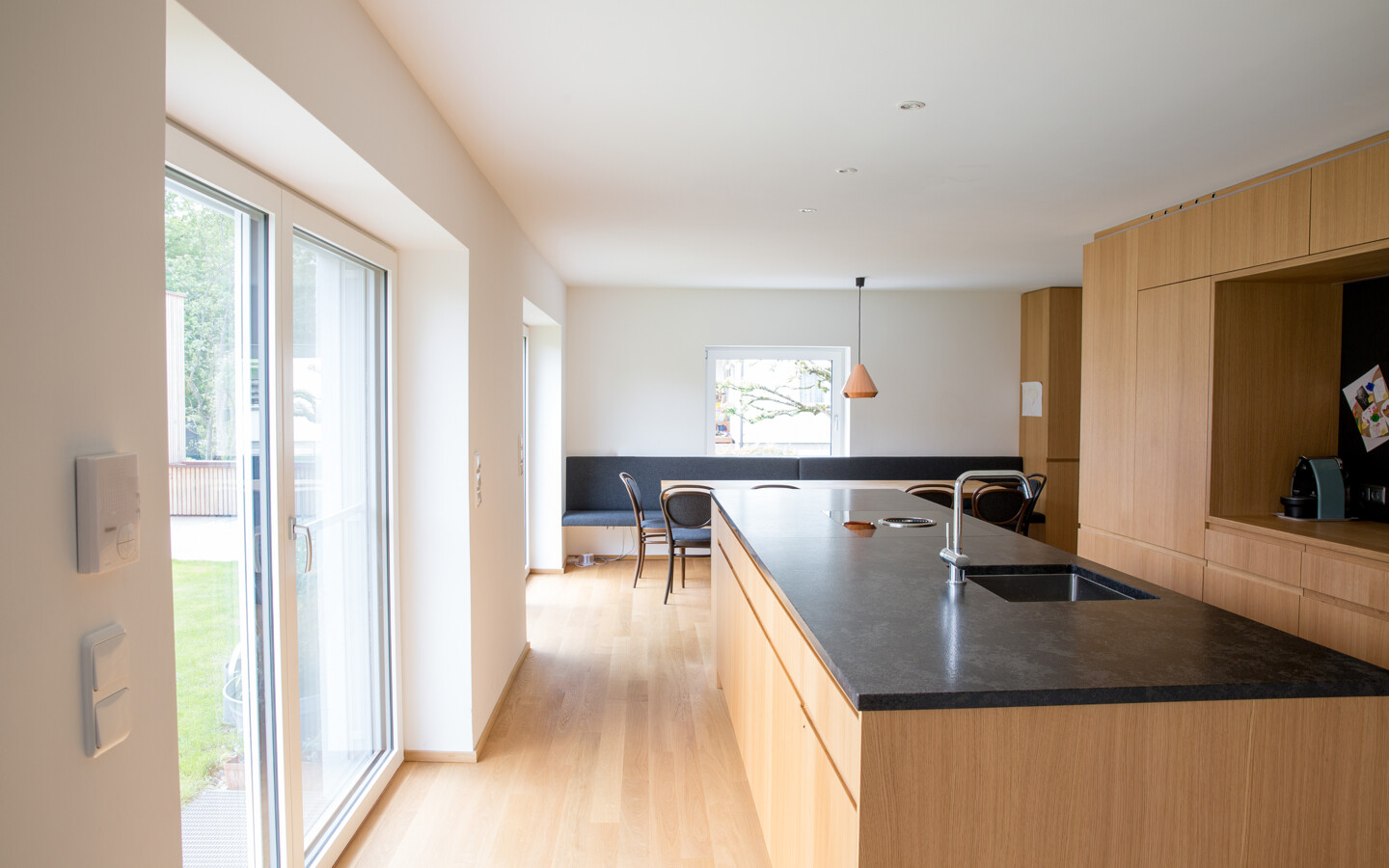Umbau Einfamilienhaus Greussing-Pallavicini Küche mit Holzausstattung und Balkonfenster nach draußen
