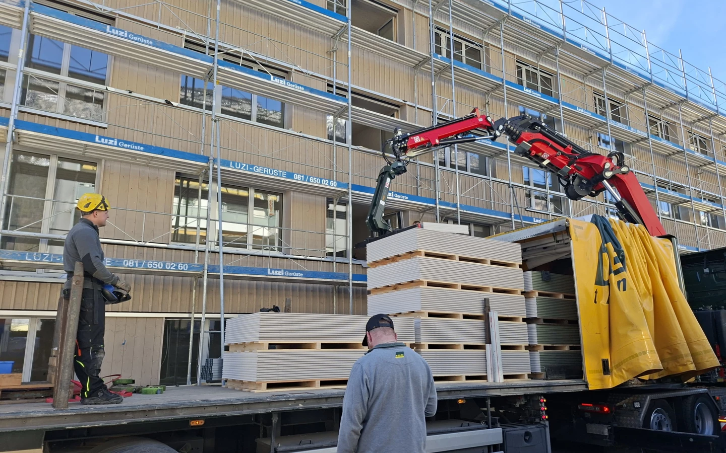 Anlieferung von Baumaterialien auf der Baustelle des Holzbauprojekts in Domat/Ems