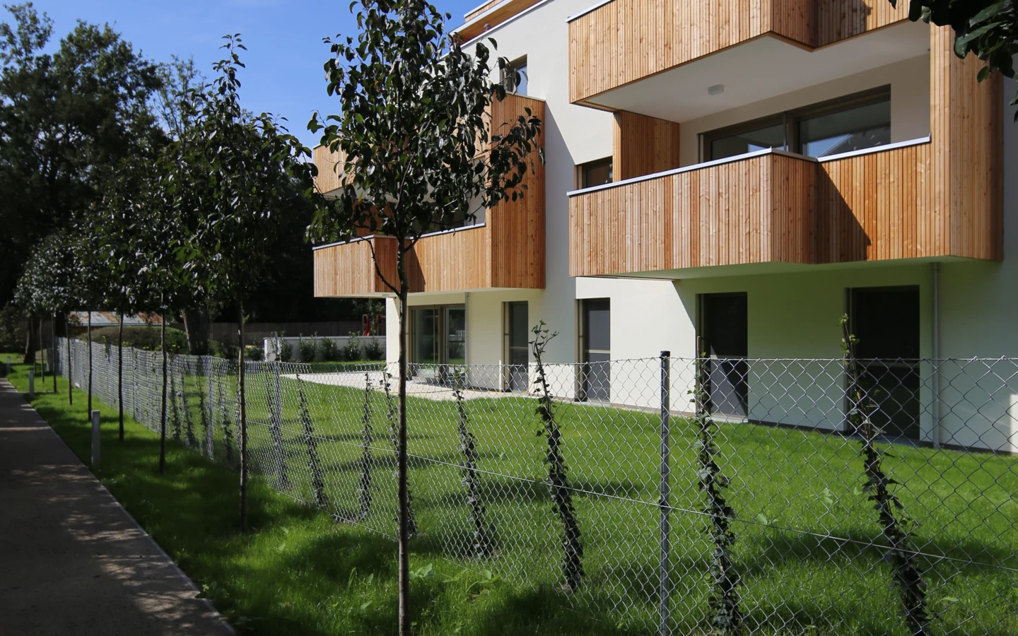 TROY_ALTM (10) Aussenansicht von Garten mit Zaun, Straße und Balkons TROY_ALTM (10) Aussenansicht von Garten mit Zaun, Straße und Balkons