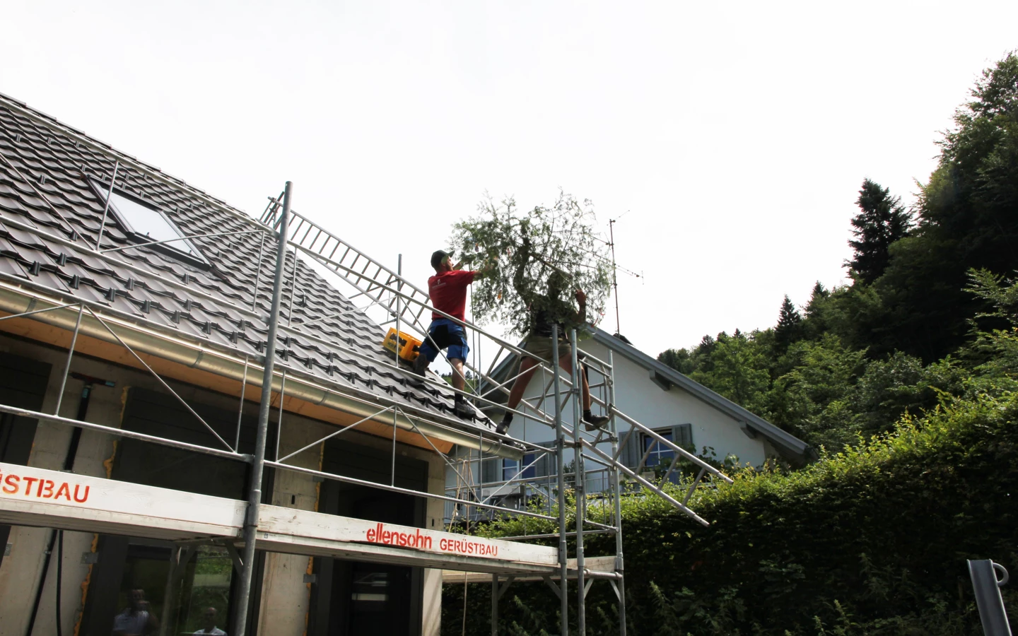 Handwerker beim Aufziehen des Firstbaumes auf den Rohbau der Wohnanlage im Dornbirner Eulental.