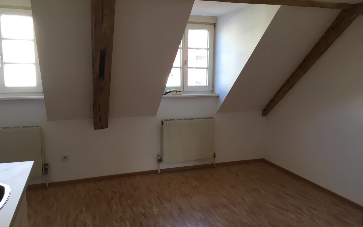 Dachboden mit Dachschräge, leerer Raum mit Holzboden und Fenster nach draußen