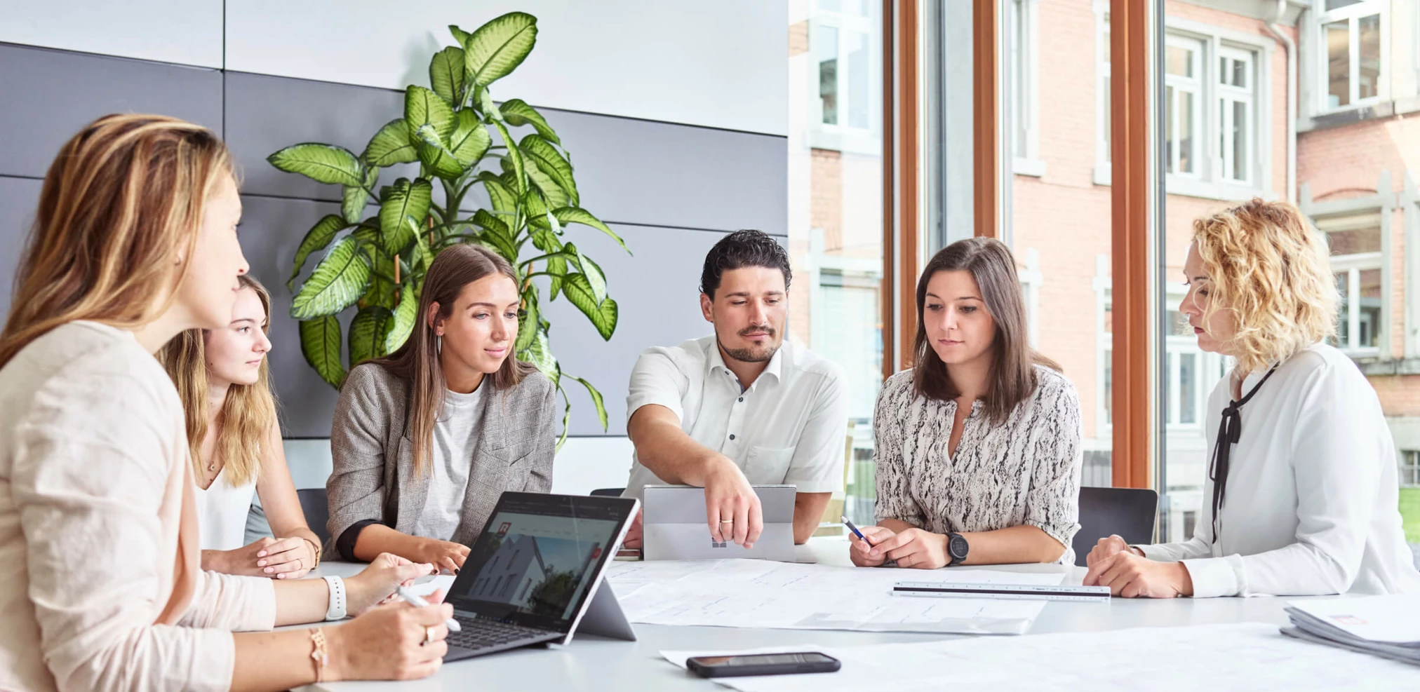 Mitarbeiter am Arbeitsplatz Büro Office Tablet Laptop Besprechung großer Tisch