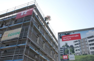 Die erste von zwei Dachgleichen: Der Firstbaum wird auf das fünfstöckige Holzgebäude aufgezogen.
