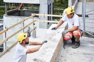 Angebot Mitarbeiter Rhomberg Bau Bauarbeiter, die sich auf Baustelle unterhalten