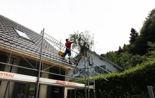 Handwerker beim Aufziehen des Firstbaumes auf den Rohbau der Wohnanlage im Dornbirner Eulental. Handwerker beim Aufziehen des Firstbaumes auf den Rohbau der Wohnanlage im Dornbirner Eulental.
