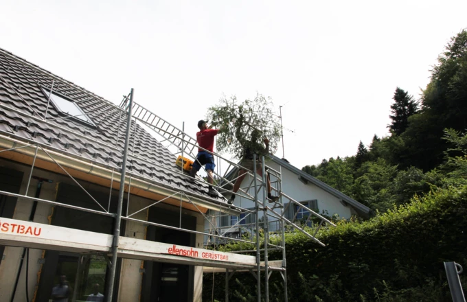 Handwerker beim Aufziehen des Firstbaumes auf den Rohbau der Wohnanlage im Dornbirner Eulental.