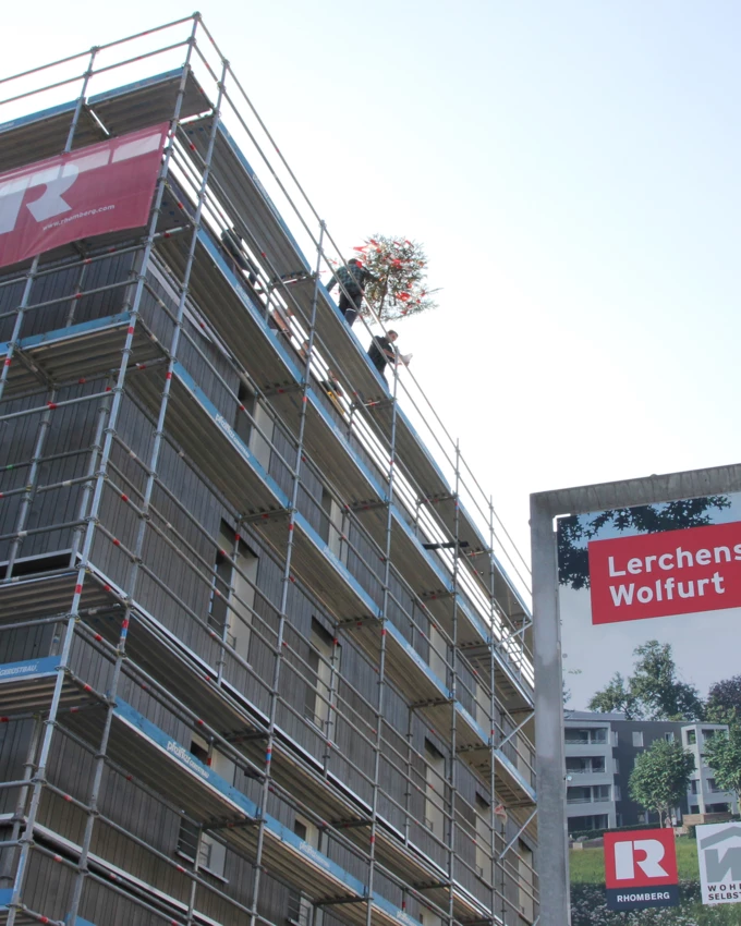 Die erste von zwei Dachgleichen: Der Firstbaum wird auf das fünfstöckige Holzgebäude aufgezogen.