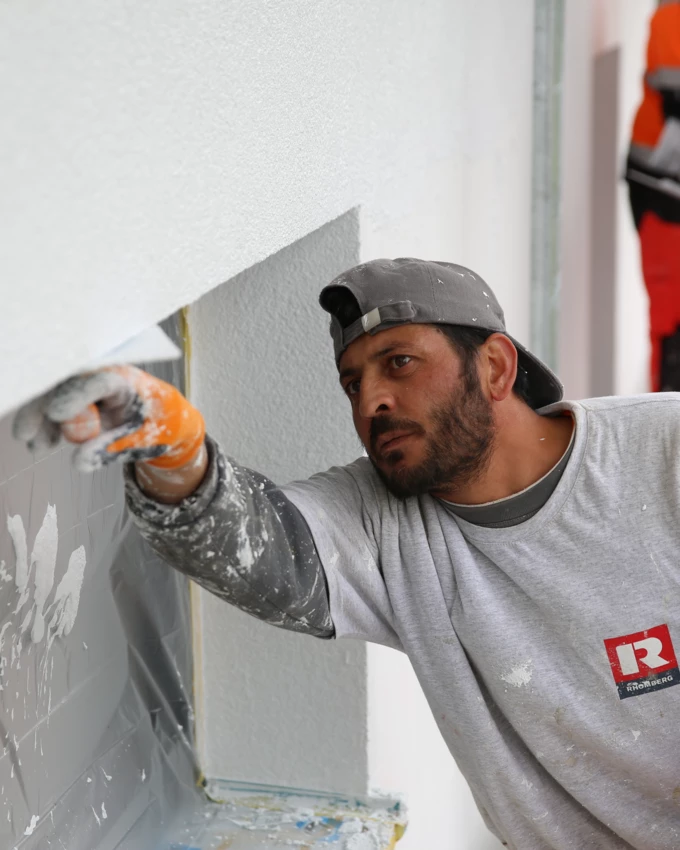 Hochbau Verputzarbeiten Mann verputzt Fenster