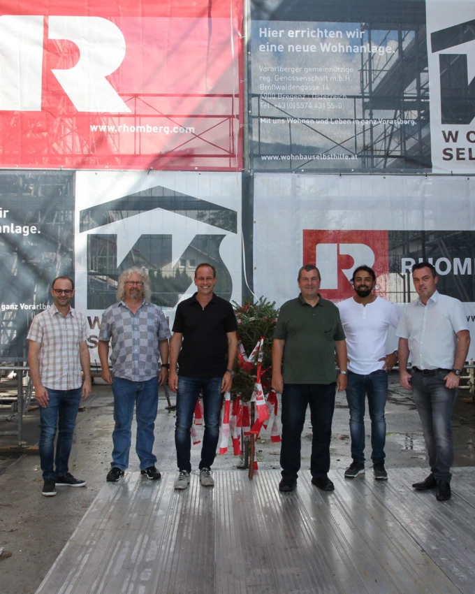 Feierten gemeinsam mit den Handwerkern die Dachgleiche (v. l. n. r.): Jürgen Loacker und Roland Obrist von der Wohnbauselbsthilfe (WH), Bürgermeister Dieter Egger, WH-Geschäftsführer Erich Mayer sowie Gökhan Ülker und Harald Hutter von Rhomberg Bau. Bildnachweis: Rhomberg Bau