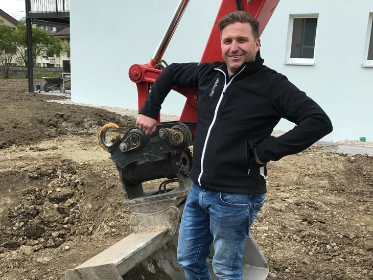Bruno Haltiner auf Baustelle steht in Baggerschaufel Bruno Haltiner auf Baustelle steht in Baggerschaufel