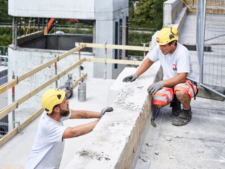 Angebot Mitarbeiter Rhomberg Bau Bauarbeiter, die sich auf Baustelle unterhalten Angebot Mitarbeiter Rhomberg Bau Bauarbeiter, die sich auf Baustelle unterhalten