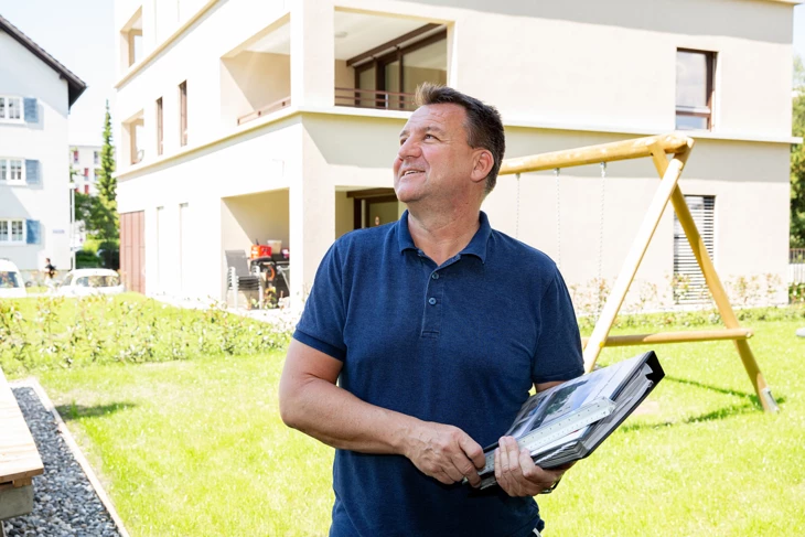 Franz Pircher mit Aktenmappe vor Spielplatz begutachtet Gebäude