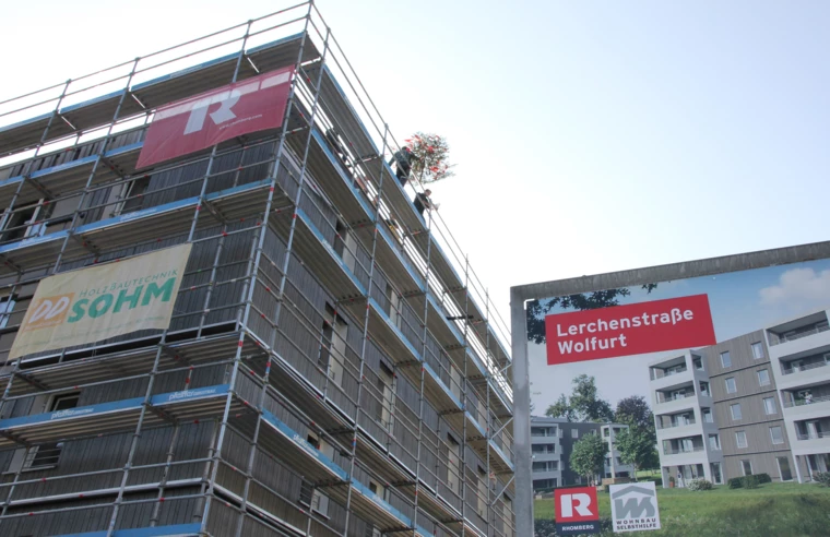 Die erste von zwei Dachgleichen: Der Firstbaum wird auf das fünfstöckige Holzgebäude aufgezogen.