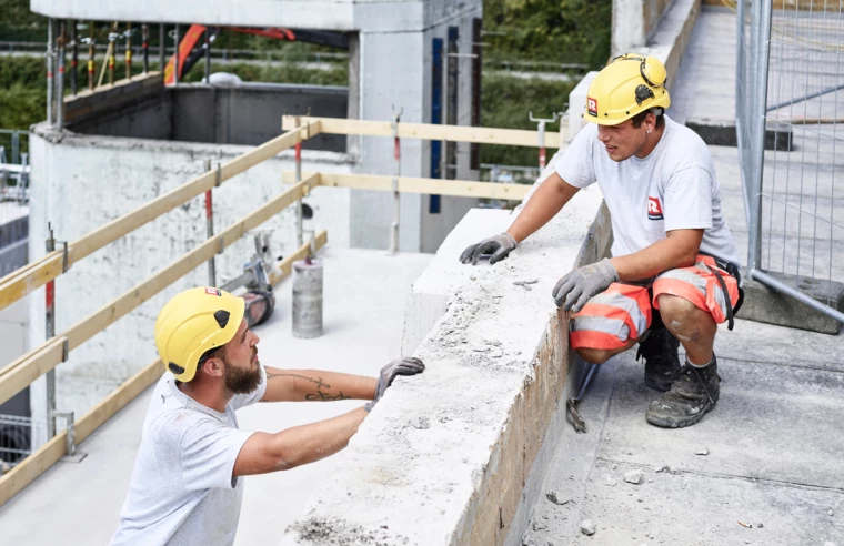 Angebot Mitarbeiter Rhomberg Bau Bauarbeiter, die sich auf Baustelle unterhalten