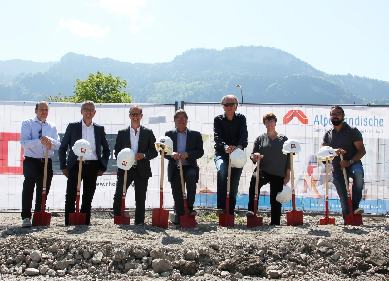 Gruppenbild mit Spaten: Christian Jauk und Martin Summer von Rhomberg Bau, Bürgermeister Dieter Egger, AH-Geschäftsführer Ing. Wilhelm Muzyczyn, Architekt DI Reinhard Drexel, Alexandra Schalegg von der Alpenländischen sowie Rhomberg-Bauleiter Gökhan Ülker feierten bei strahlendem Sonnenschein den Baustart der Wohnanlage in der Wasenstraße.