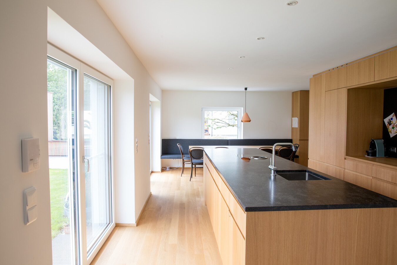 Umbau Einfamilienhaus Greussing-Pallavicini Küche mit Holzausstattung und Balkonfenster nach draußen